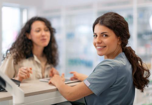 A smiling front desk staff looking at the camera after a patient left a review at the dental practice station.